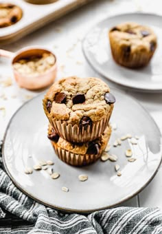 two chocolate chip muffins stacked on top of each other with oats scattered around them