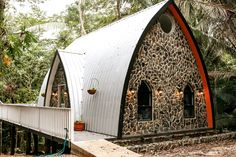 a building made out of giraffe print material in the forest with trees and plants around it