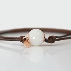 Beautiful handmade item! Here, on Etsy made as simulation only-just resin and white color.  Breastmilk pearl beaded bracelet with 1mm brown waxed cord.  Our  Simple Pearl Beads Bracelet is a pure and simple celebration of the natural beauty of motherhood. Sterling silver core in the central bead (rose or yellow gold options available). Add pearl powder for lustrous effect.  For all our breast milk bracelet collection, please visit: https://www.etsy.com/ca/shop/KeepsakeMom?ref=seller-platform-mcnav&section_id=27169694 For all breastmilk jewelry, please visit:  https://www.etsy.com/ca/shop/KeepsakeMom?ref=seller-platform-mcnav BREASTMILK JEWELRY NOTICE: For jewelry made with your own breast milk, please visit www.KeepsakeMom.com ETSY PROHIBITS THE SALE OF JEWELRY MADE WITH BREAST MILK; We se Everyday White Waxed Cord Bracelets, Handmade White Jewelry With Waxed Cord, White Waxed Cord Bracelet Perfect For Gifting, White Waxed Cord Bracelet As A Gift, White Waxed Cord Bracelets For Gifts, Jewerly Bracelets, Breastmilk Jewelry, Silver Core, Simple Pearl