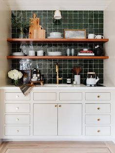 a kitchen with white cabinets and green tiled backsplash