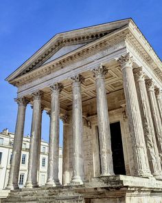 an old building with columns and pillars on the outside, in front of a blue sky