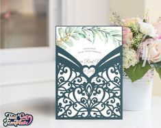 the wedding card is next to a vase with flowers