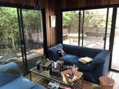 a living room filled with blue furniture and lots of glass doors leading to an outside deck