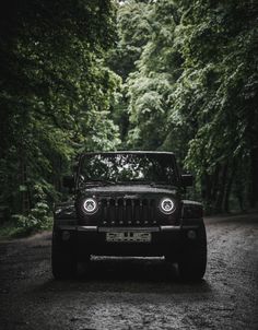 a black jeep parked in the middle of a forest