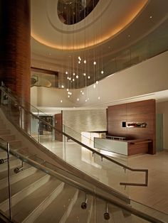 a staircase leading up to a lobby with lights hanging from it's ceiling and two sets of handrails