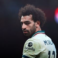 a close up of a man with curly hair wearing a rugby jersey and looking off to the side