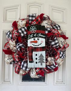 a red and black wreath with a snowman on it that says let it snow