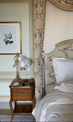 a bed with white sheets and pillows next to a painting on the wall above it