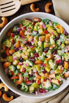 a white bowl filled with broccoli salad and nuts