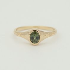 a gold ring with a green stone on it's center and an oval shaped band