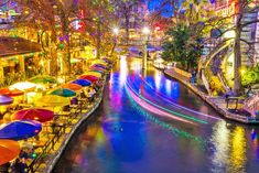 an image of a river that is lit up at night with umbrellas in the foreground