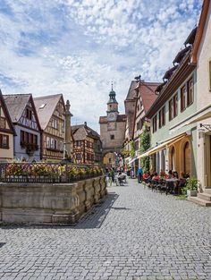 a cobblestone street lined with buildings and people sitting at tables