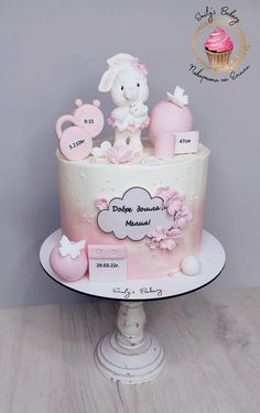 a pink and white cake decorated with baby items