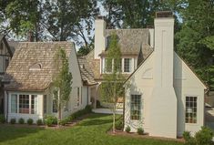 a white house with brown shingles and trees in the background