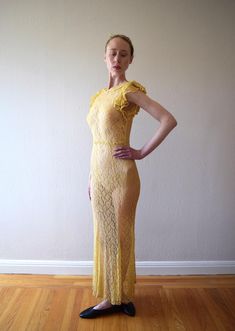 A vintage 1930s yellow lace gown with a small collar, ruffled flutter sleeves, and a low back. The lace fabric feels like cotton. There are no fasteners, but the fabric has give to fit over bust/shoulders. Size: xxs to small Bust: 28-34" Waist: 26-32" (will drape fine on slightly smaller, and 32" waist will need to fit over bust/shoulders because there are no fasteners at waist) Hip: 30-38" Length: 59-60" (will drape slightly shorter when dress is worn) Condition: Very good. Darkening in underarms and slight darkening at hem, but because of location, these flaws wouldn't be noticeable when dress is worn. A few tiny breaks in lace that look like part of pattern. Dress has been hand washed and presents as excellent. Fitted Maxi Length Lace Dress With Scalloped Lace, Fitted Floor-length Lace Dress With Scalloped Lace, Fitted Maxi Lace Dress With Ruffles, Fitted Maxi Length Lace Dress With Ruffles, Yellow Maxi Dress With Ruffles For Wedding, Yellow Lace Maxi Dress For Party, Yellow Wedding Maxi Dress With Ruffles, Fitted Yellow Lace Dress, Yellow Fitted Lace Dress