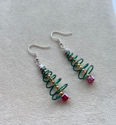 Christmas Tree Earrings, Festive Wire Tree Earrings, Cute Spiral Xmas Tree Jewellery Quirky festive Christmas tree earrings, easy and super fun to wear These earrings are wire wrapped with enamelled wire, a golden centred branch sitting in a red crystal bucket and a tiny little silver star topper. Size: 6 cm from top of the hook 4.5 cm drop Care: Instruction: In order to keep your jewellery in perfect condition, we always advice keeping items out of contact with any chemicals, strong perfume or Nickel-free Earrings For Christmas Party, Adjustable Earrings For Christmas Gift, Adjustable Earrings As A Christmas Gift, Green Earrings New Year Gift, Green Earrings For New Year Gift, Green Earrings Gift For New Year, Green Christmas Earrings, Wire Xmas Tree, Holiday Beaded Jewelry