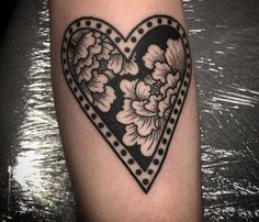 a black and white heart with flowers on it's side, sitting on top of a table