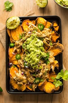 a black tray filled with nachos and guacamole