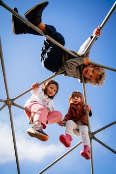 three children are climbing up and down a metal structure