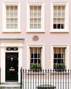 a pink building with white windows and black iron fence on the street in london, england