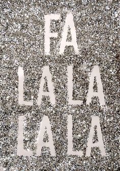 the word fa la la la written in white letters on a silver glittered surface