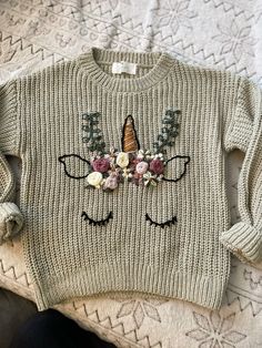 a sweater with an image of a unicorn's face and flowers on the front