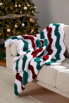 a couch with a blanket on it next to a christmas tree