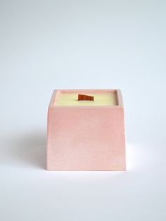 a small square candle holder with a wooden stick sticking out of it