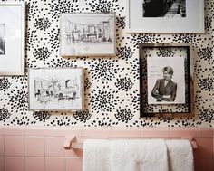 black and white wallpaper in a bathroom with pictures on the wall, towels hanging up next to it