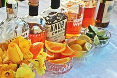 several bottles of alcohol sitting on top of a table next to oranges and flowers