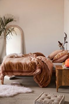 a bed sitting in a bedroom next to a table with pillows on top of it