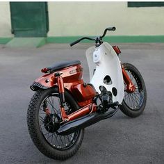 an orange and white motorcycle parked in a parking lot