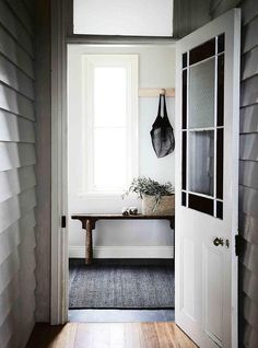 an entryway with a bench, window and coat rack on the door way to another room