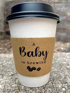 a coffee cup with the words baby is brewing on it sitting on top of a stone surface