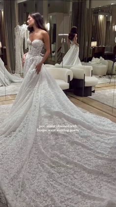 a woman standing in front of a mirror wearing a wedding dress