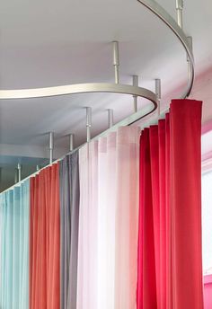 colorful curtains are hanging from the ceiling in front of a window with a circular curtain rod