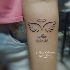 a tattoo with an angel wings on the arm and date in roman numerals