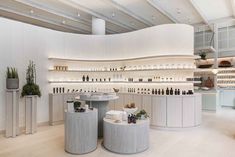 the inside of a store with white walls and shelves filled with bottles, vases and plants