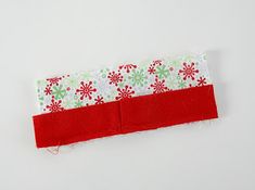 a red and white piece of fabric with snowflakes on it sitting next to a pair of scissors