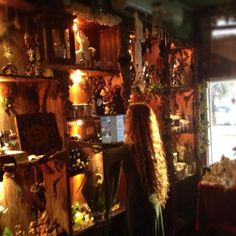 a woman with long hair standing in front of a shelf filled with clocks and other items