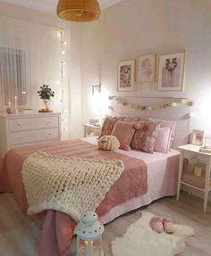 a bedroom decorated in pink and white with pictures on the wall