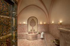 a bath room with a large tub and candles on the wall next to an open door