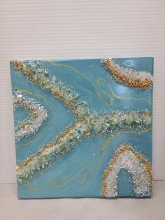 an abstract painting with blue and gold colors on it's surface, in the middle of a white wall