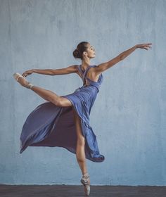 a woman in a blue dress is dancing with her legs spread out and arms outstretched