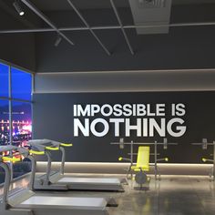 there is a gym with treadmills and exercise equipment in the room that says impossible is nothing