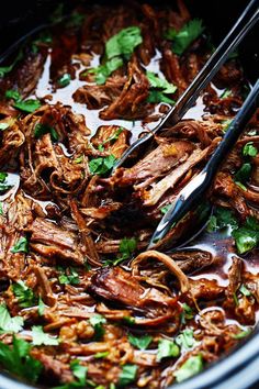 a bowl filled with pulled pork and garnished with cilantro, parsley