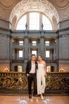 a man and woman standing next to each other in front of a large room with high ceilings