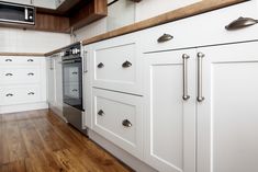 a kitchen with white cabinets and wood flooring, including an oven in the center