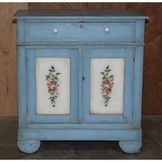 an old blue cabinet with flowers painted on it