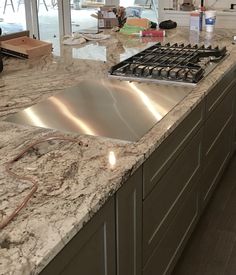 a kitchen with marble counter tops and stainless steel stove top, oven door open to the dining room